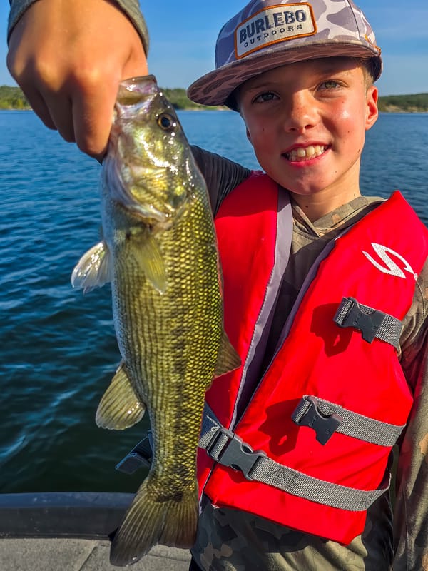 Young angler with a Guadalupe bass caught along a rocky bank on Lake Travis