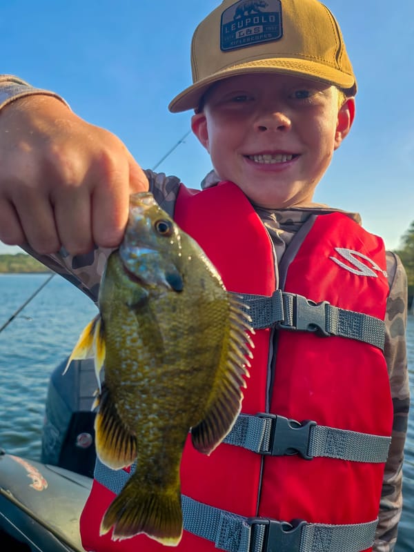 Smiling young angler holding a big sunfish on a family fishing trip on Lake Travis