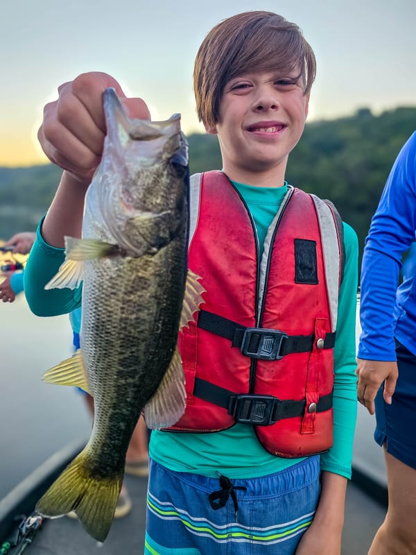 Young angler holding a Lake Austin largemouth bass at sunrise on a family fishing trip