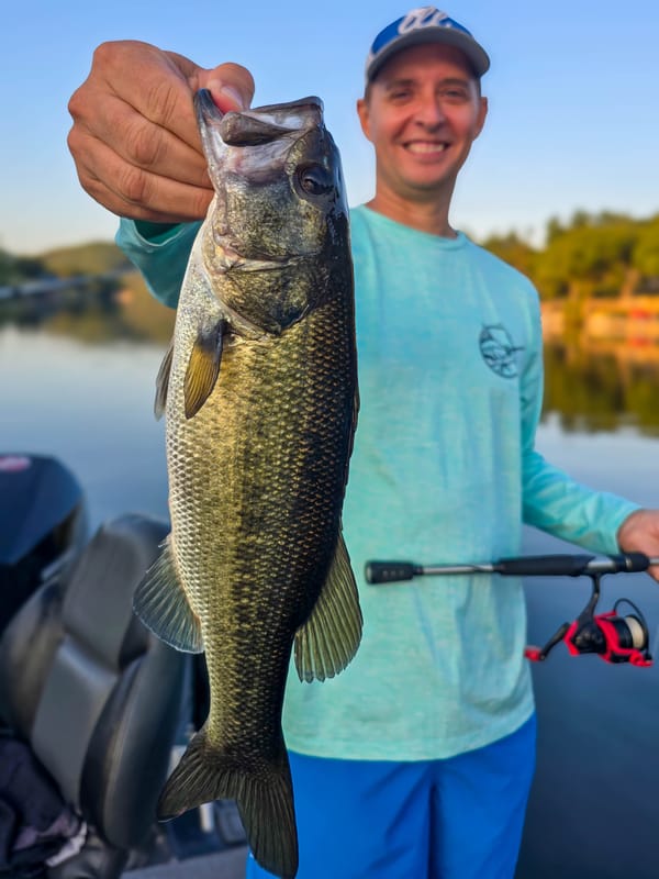 Angler with a solid largemouth bass caught on a soft plastic creature bait on Lake Austin