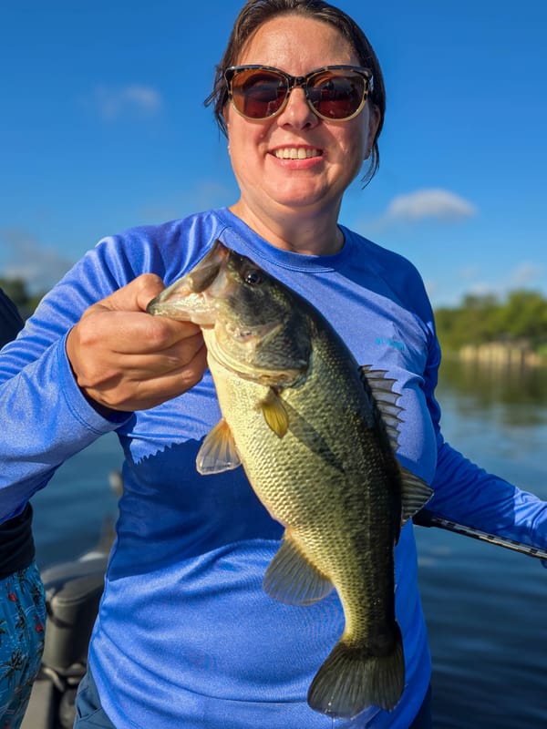 Smiling angler with a healthy largemouth bass under blue skies on Lake Austin