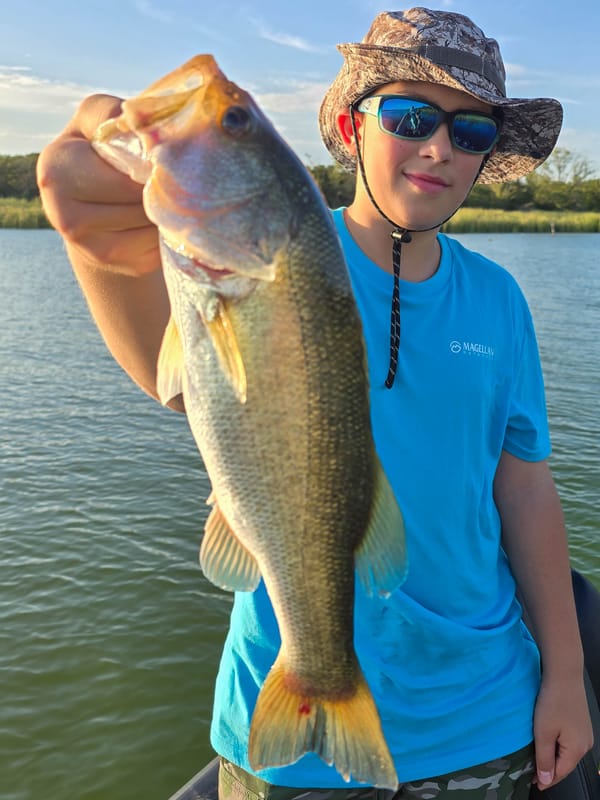 Young angler holding a largemouth bass in golden evening light at Lake Bastrop
