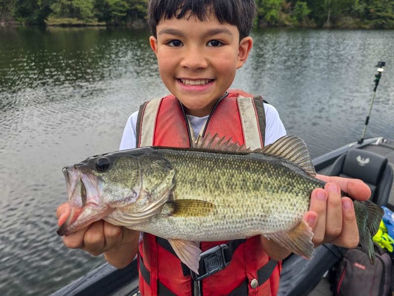 Young angler holding a largemouth bass caught on a creature bait at Lake Austin