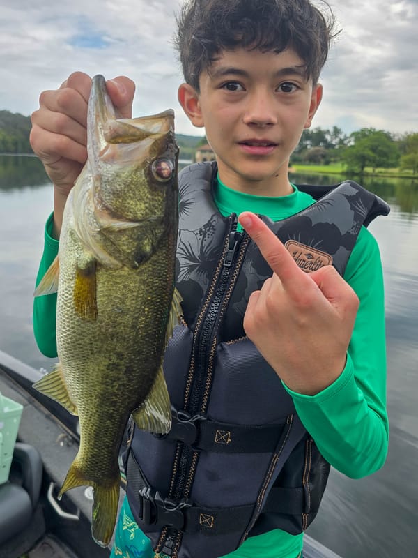 Young angler pointing at a chunky Lake Austin largemouth bass