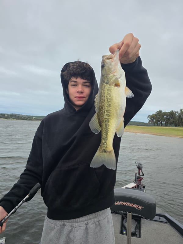 Young angler holding a Lake Travis largemouth bass on a windy October morning