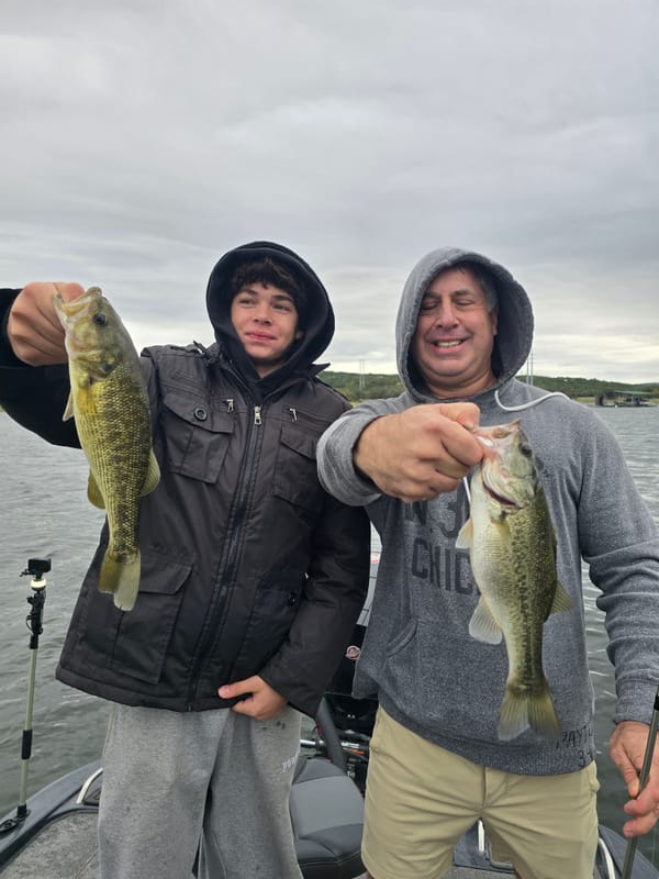 Father and son each holding a largemouth bass caught on creature baits on Lake Travis