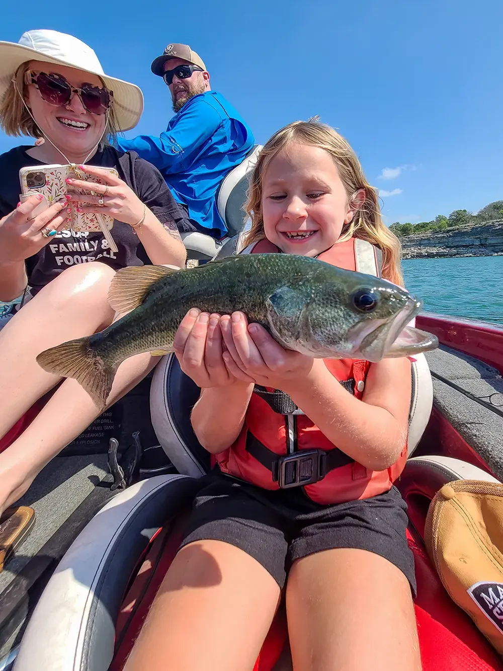 A young girl holding a bass she caught on a Texas Hawgs trip