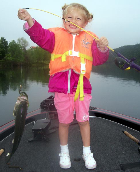 Young girl in a life jacket catching a fish on Lake Austin, April 2006